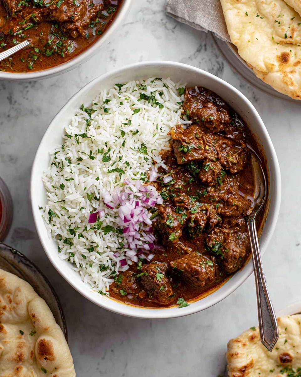 The image shows a white bowl filled with two main layers: on one side, white rice sprinkled with green herbs, showing a fluffy and separated texture; on the other side, a thick brown stew with pieces of tender meat in a rich sauce, topped with small bits of chopped red onion and green herbs, adding color contrast. A silver spoon rests on the rice side, and the bowl is placed on a white marbled surface. Other dishes and naan bread are partially visible around the bowl, enhancing the meal setting. photo taken with an iphone --ar 4:5 --v 7