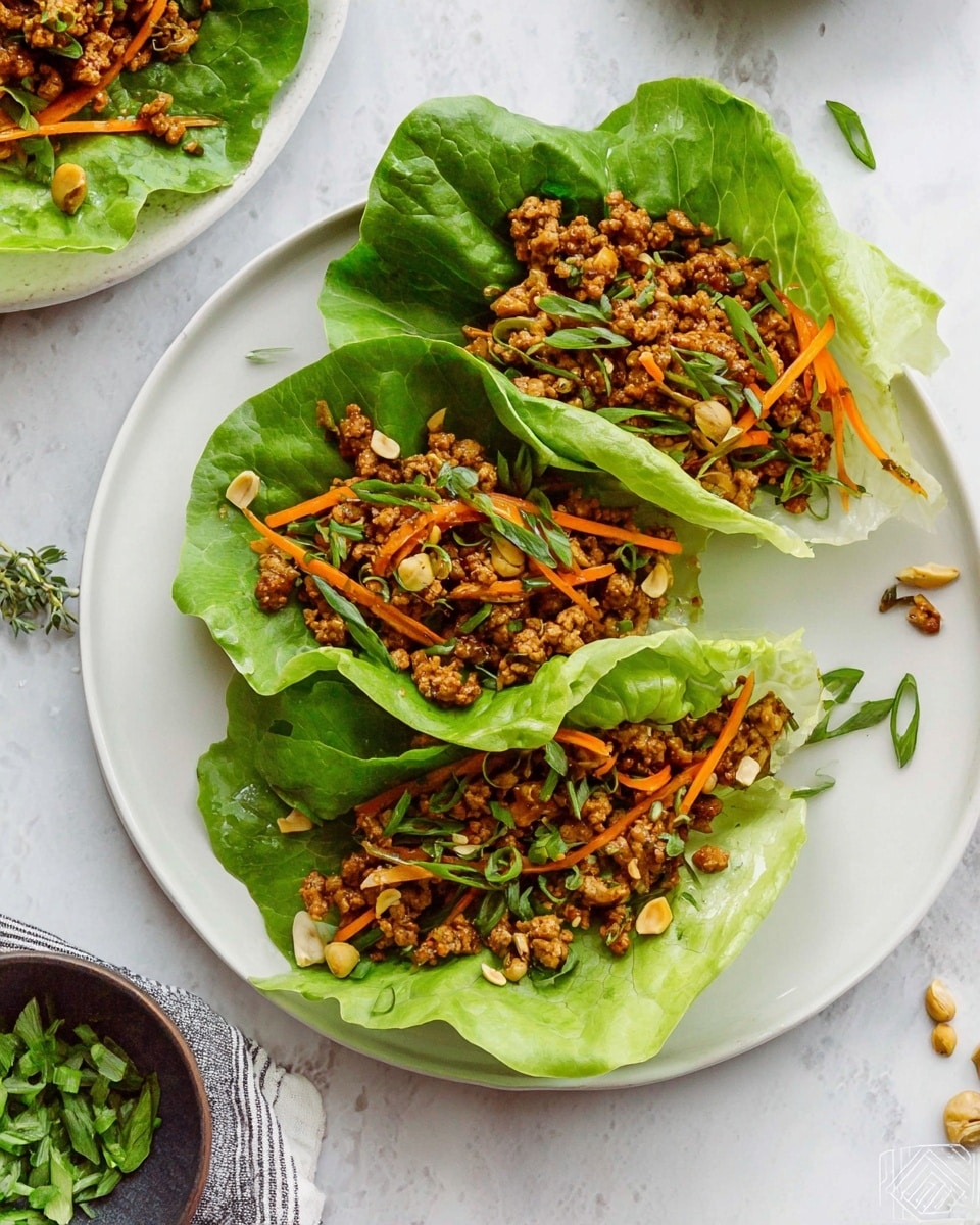 There are three lettuce cups on a white plate, each filled with a mixture of ground meat that is golden brown, thin orange carrot strips, light brown cashew nuts, and bright green sliced scallions, sprinkled with white sesame seeds. The lettuce leaves are bright green and fresh, forming a bowl-like shape holding the filling. A woman's hand is holding one of the lettuce cups from the left side of the image. The plate is set against a white marbled surface, with a partial view of a glass bowl filled with more of the meat mixture on the top left corner. photo taken with an iphone --ar 4:5 --v 7