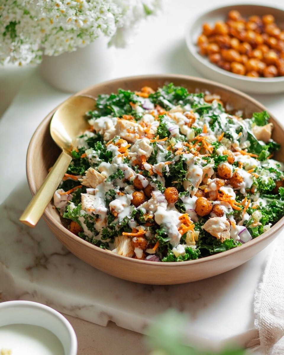 The image shows a bowl of mixed salad with several layers; at the bottom are green leafy kale pieces, topped with orange-brown roasted chickpeas and small white chunks of chicken scattered throughout. Over these layers is a drizzle of creamy white dressing with a slightly speckled texture. A gold spoon rests inside the bowl, partially buried in the salad. The bowl is white and sits on a white marbled surface, surrounded by a small white bowl of chickpeas on the left and a white bowl of dressing at the bottom right, with yellow flowers blurred in the background. Photo taken with an iphone --ar 4:5 --v 7