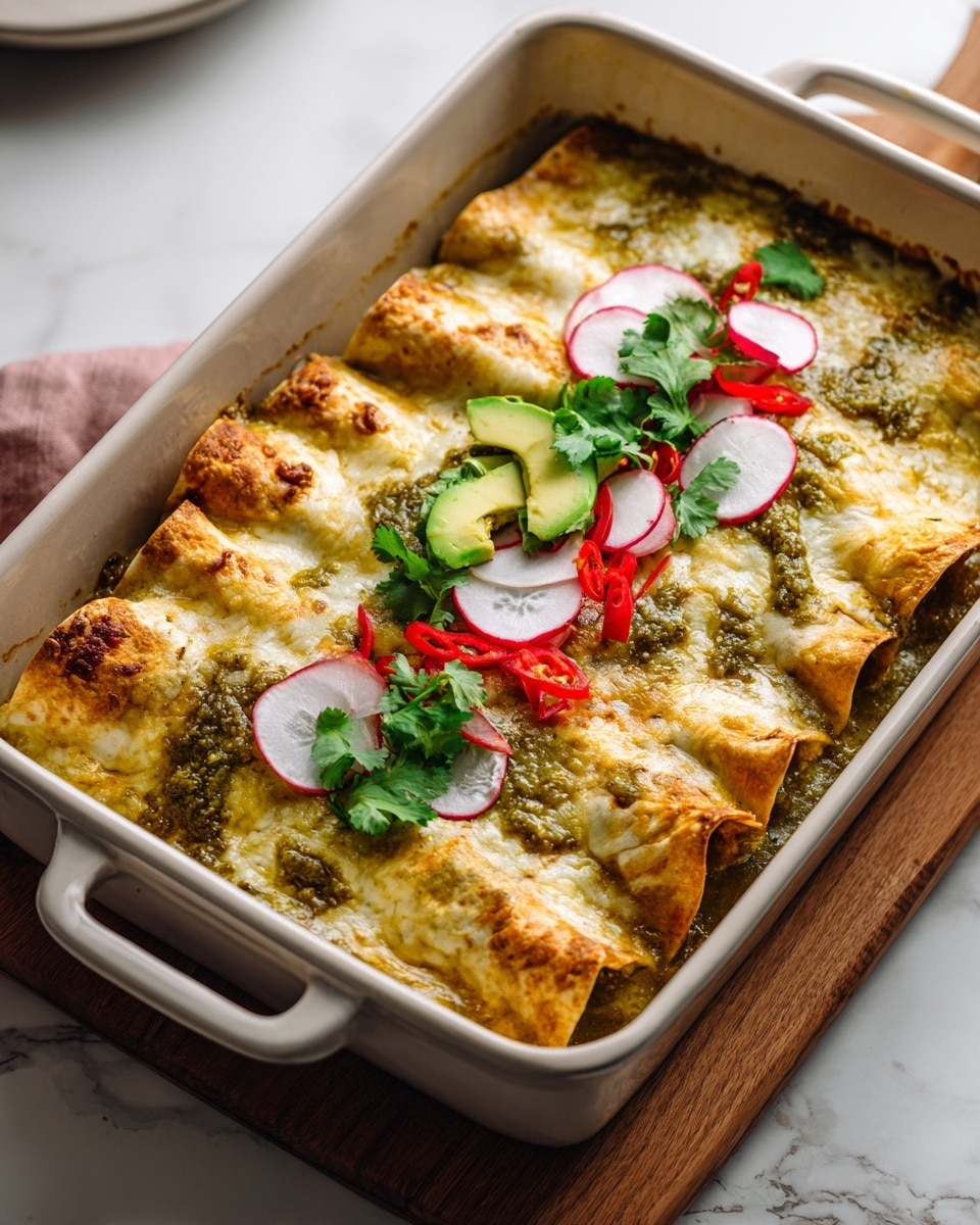 A white baking dish holds four golden-brown enchiladas layered with melted cheese and a green salsa sauce, spreading evenly across the top. On top of the enchiladas, there is a fresh decoration of thin red radish slices, bright red chili pieces, green avocado slices, and leafy cilantro, all arranged in a neat row down the center. The dish rests on a wooden board with a white marbled surface in the background, giving a clean and fresh look to the scene. photo taken with an iphone --ar 4:5 --v 7