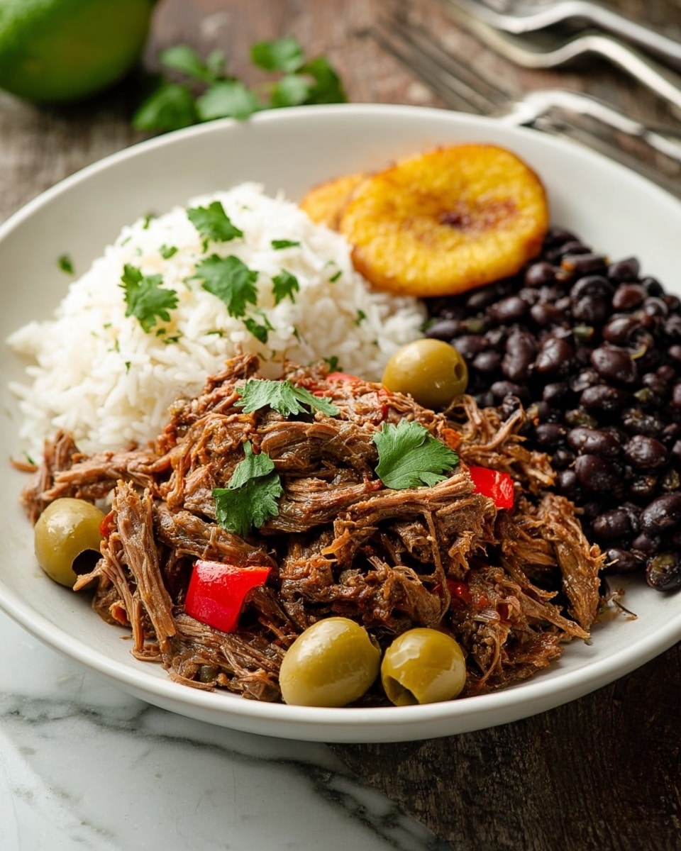 A white plate holds a meal with four main parts separated clearly: the bottom left side has shredded brown beef mixed with whole green olives and small red pieces, garnished with fresh green cilantro leaves scattered around the bottom and top edges; behind this, on the upper left, is a portion of fluffy white rice with more cilantro on top; to the upper right, there is a cluster of shiny black beans; and on the right side closest to the viewer, there is a single golden-brown fried plantain slice. The plate rests on a white marbled surface. Photo taken with an iphone --ar 4:5 --v 7