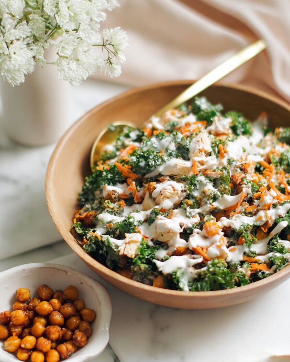 A light brown bowl filled with a fresh salad featuring chopped green kale leaves mixed with small pieces of white chicken, orange shredded carrots, and roasted golden chickpeas, all topped with a white creamy dressing that drizzles over the ingredients. A gold spoon sits in the bowl, partially buried in the salad. The bowl is set on a white marbled surface, with a small white bowl containing more roasted chickpeas nearby and a white vase with white flowers blurred in the background. photo taken with an iphone --ar 4:5 --v 7