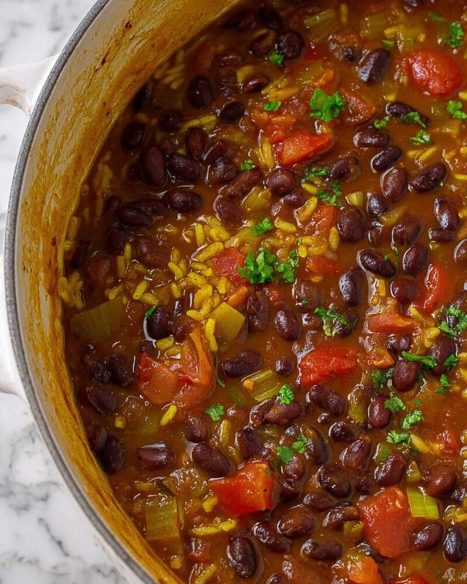 The image shows a close-up of a thick, colorful stew made of dark brown beans, yellow rice, diced red tomatoes, and chopped light green onions, all mixed in a rich brown sauce. The beans and rice are the main parts, scattered evenly with soft pieces of tomato and translucent onion throughout. Small bits of chopped fresh green herbs are sprinkled on top, adding a touch of brightness. The food looks steamy and freshly cooked, with the sauce giving a glossy texture to the ingredients. The dish is inside a white pot with some sauce residue on the edges, set against a white marbled surface. Photo taken with an iphone --ar 4:5 --v 7